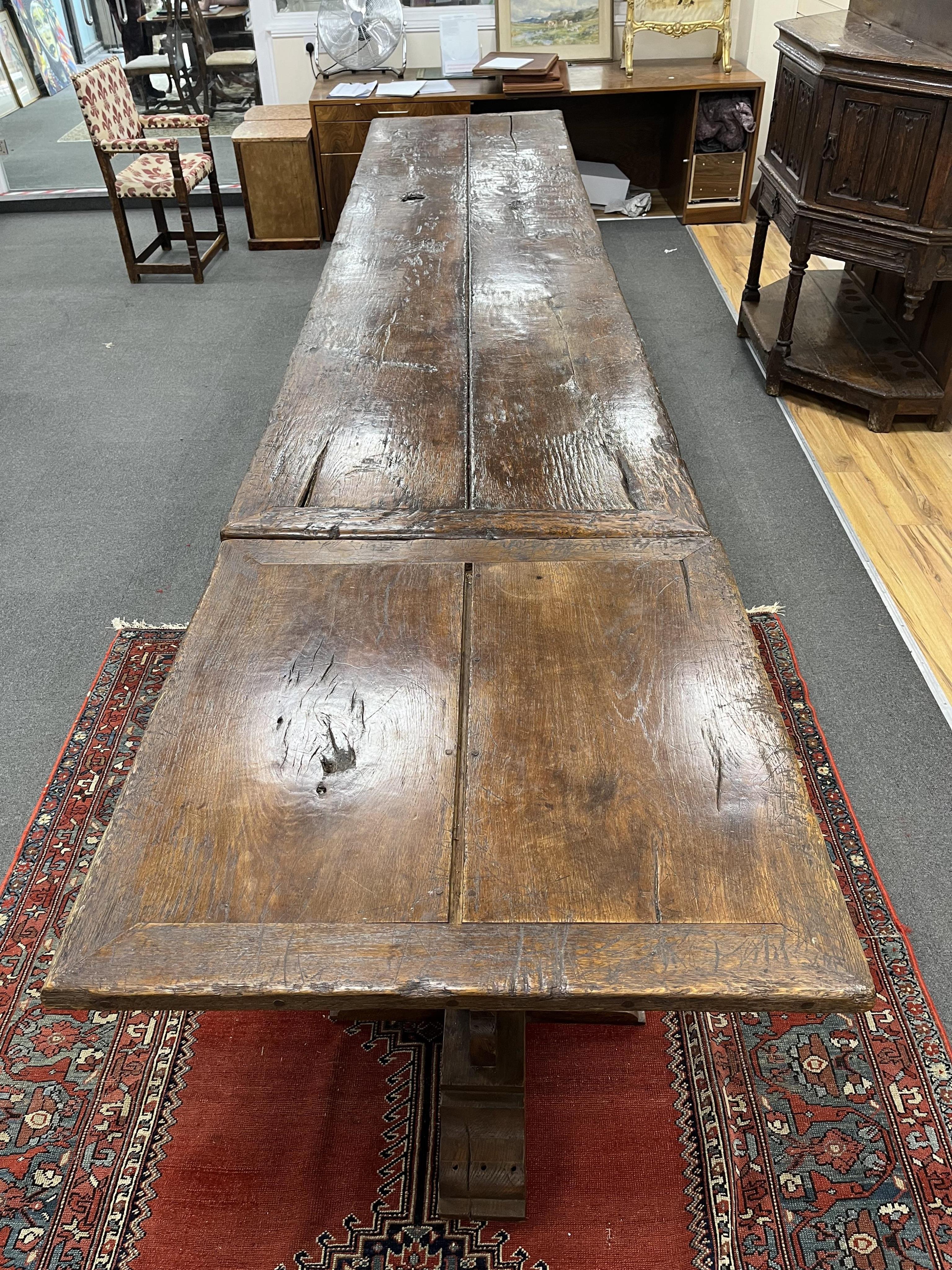 A long twin plank oak refectory dining table, in 15th century gothic style, cruciform twin pedestal base, with additional square extension table, length 365cm, 464cm with extension, depth 88cm, height 78cm. Condition - f